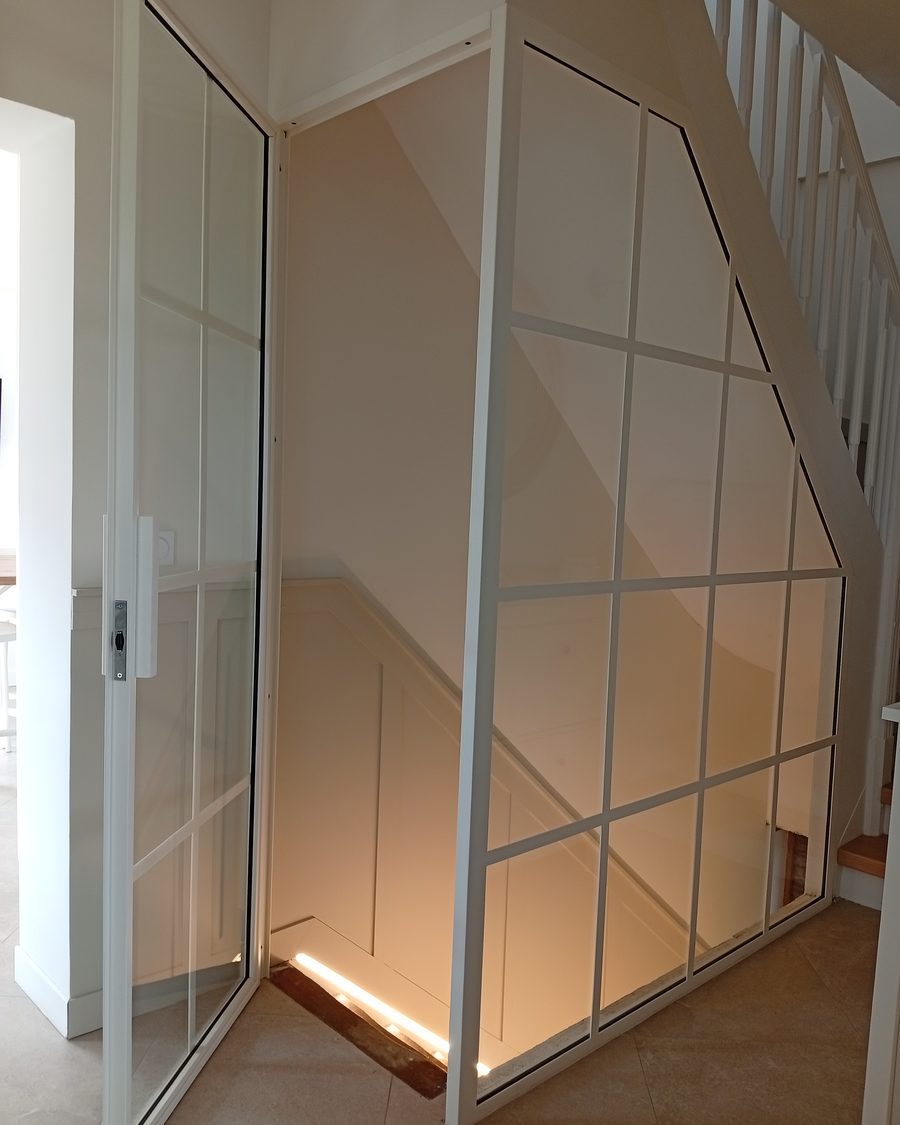 Verrière blanche toute hauteur fermant une cage d’escalier sous rampant
